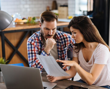 Frustrated couple checking bills at home using laptop