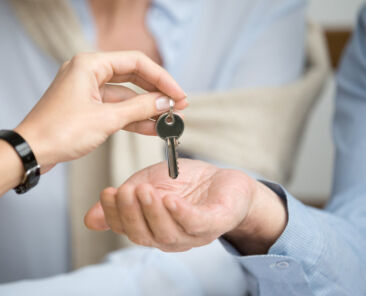 Couple of homeowners getting key to new house apartment from realtor, happy real estate owners make purchase deal, family mortgage investment and buying property concept, close up view of hands