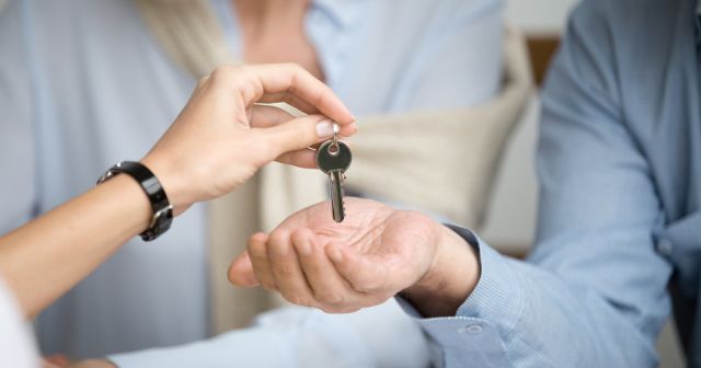 Couple of homeowners getting key to new house from realtor